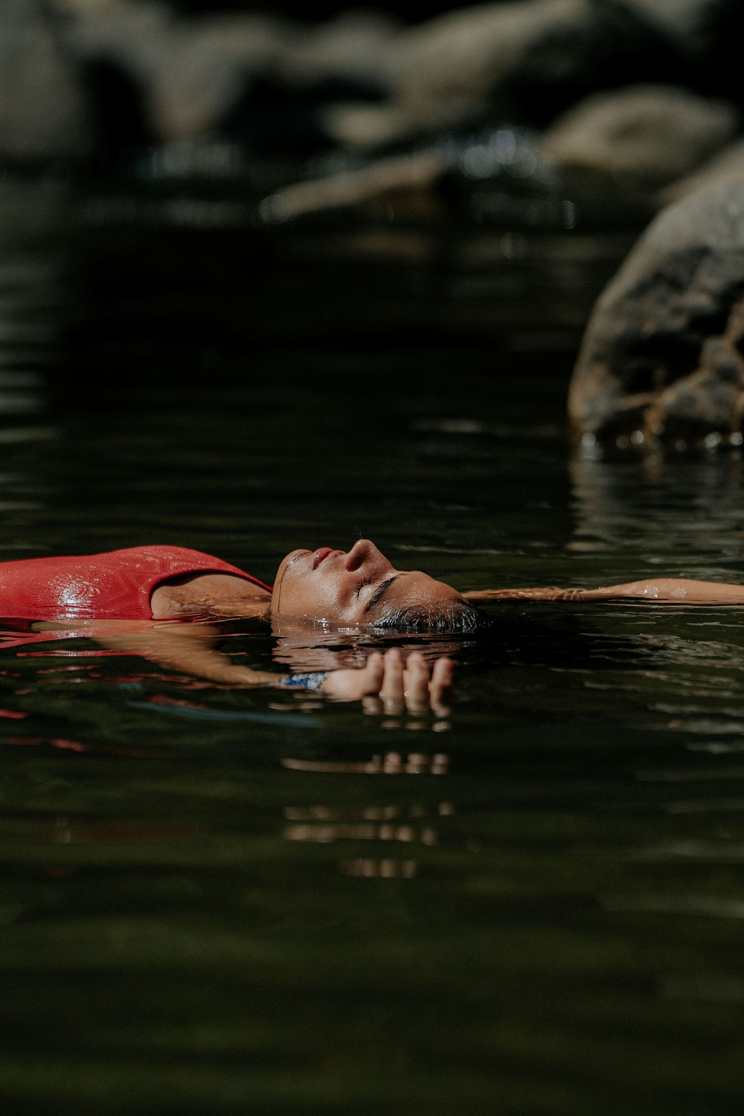 Person floating peacefully in dark water with red swimwear.
