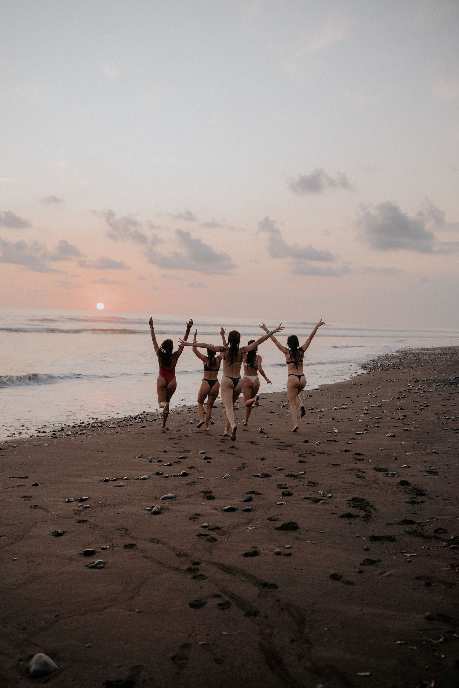 Silhouettes of friends jumping joyfully on a beach at sunset.