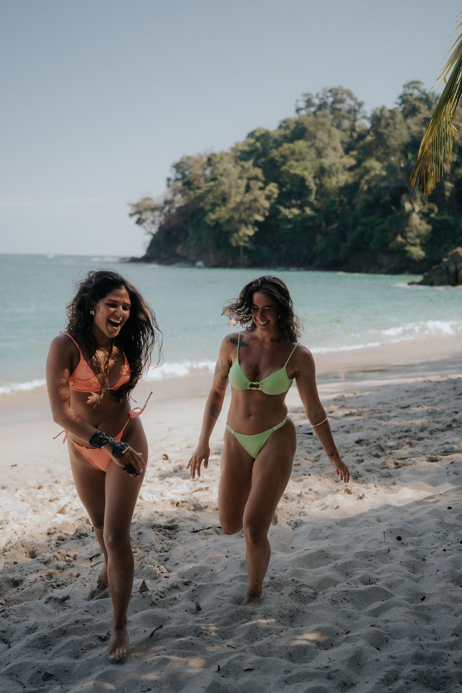 Two friends playing and running together on a scenic tropical beach.