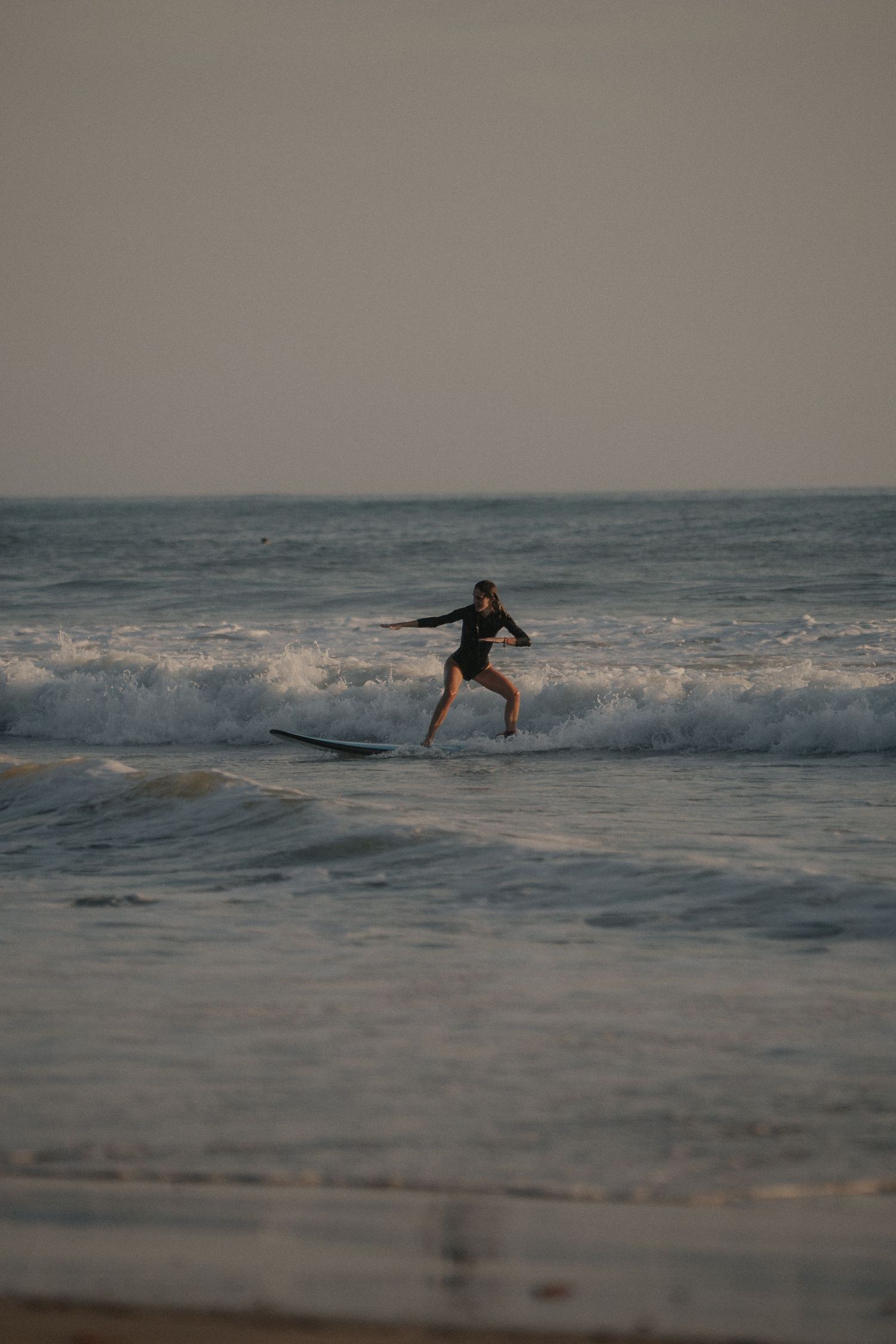 Surfer riding wave in ocean during moody evening light.