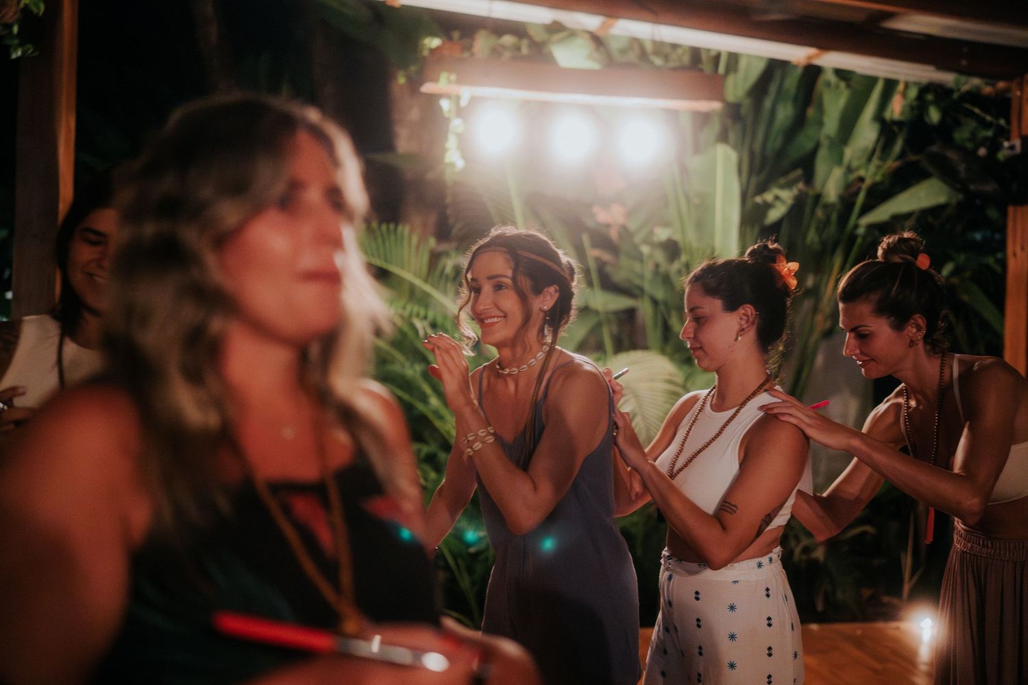 A dimly lit gathering with people socializing and dancing in the evening.