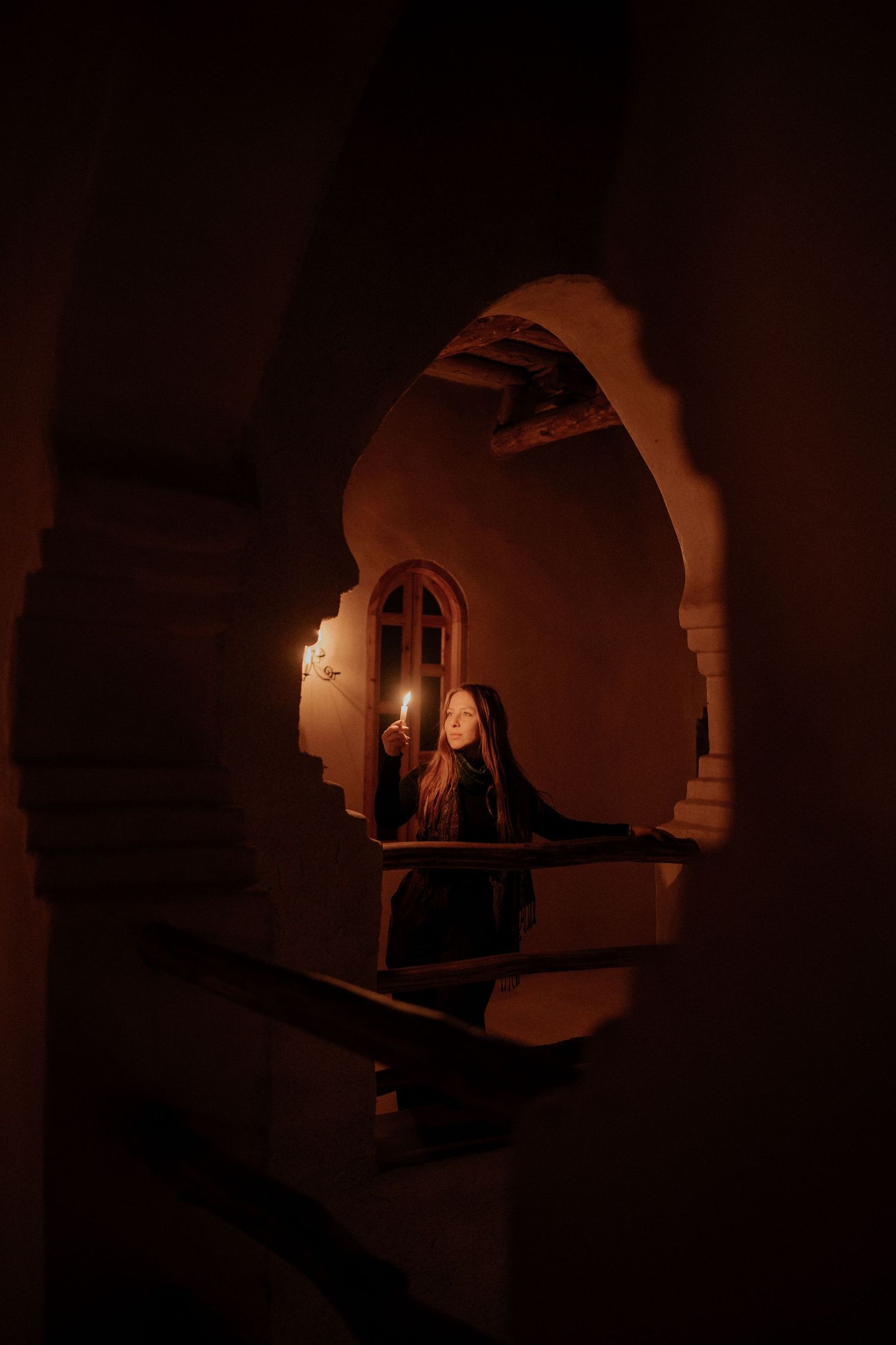 Dimly lit interior passageway with arched doorways creating mysterious shadows.