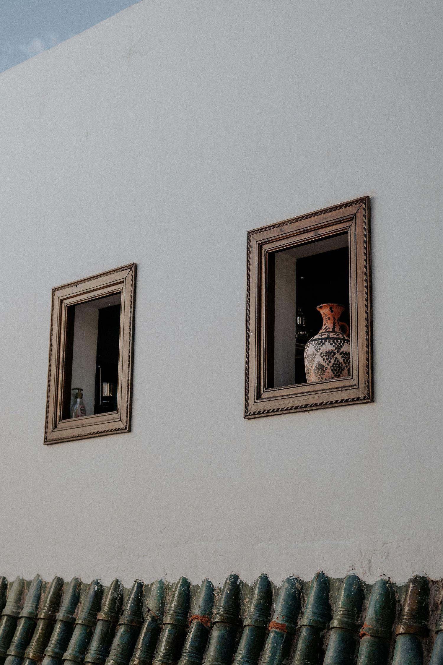 Small framed artwork displayed in a row on a white wall above green tiles.