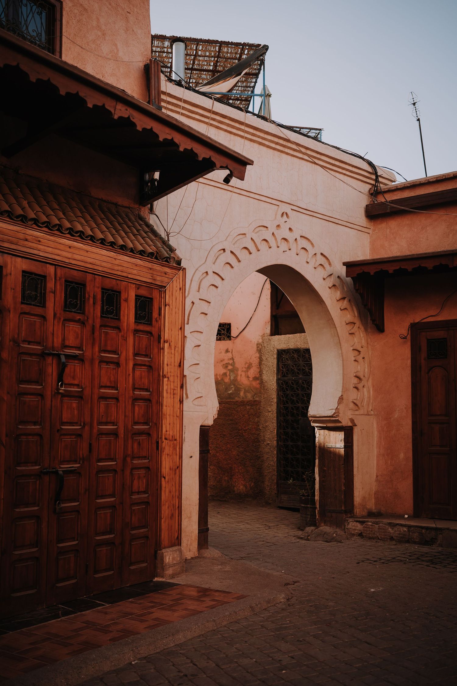 Traditional Moroccan archway and wooden doors in terracotta colored courtyard.