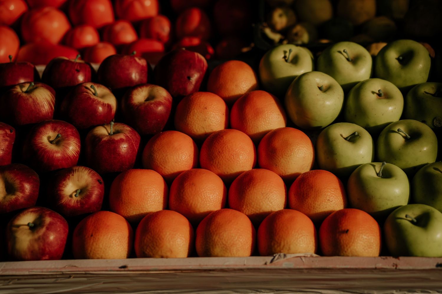 Colorful display of red, orange and green apples neatly arranged in rows.