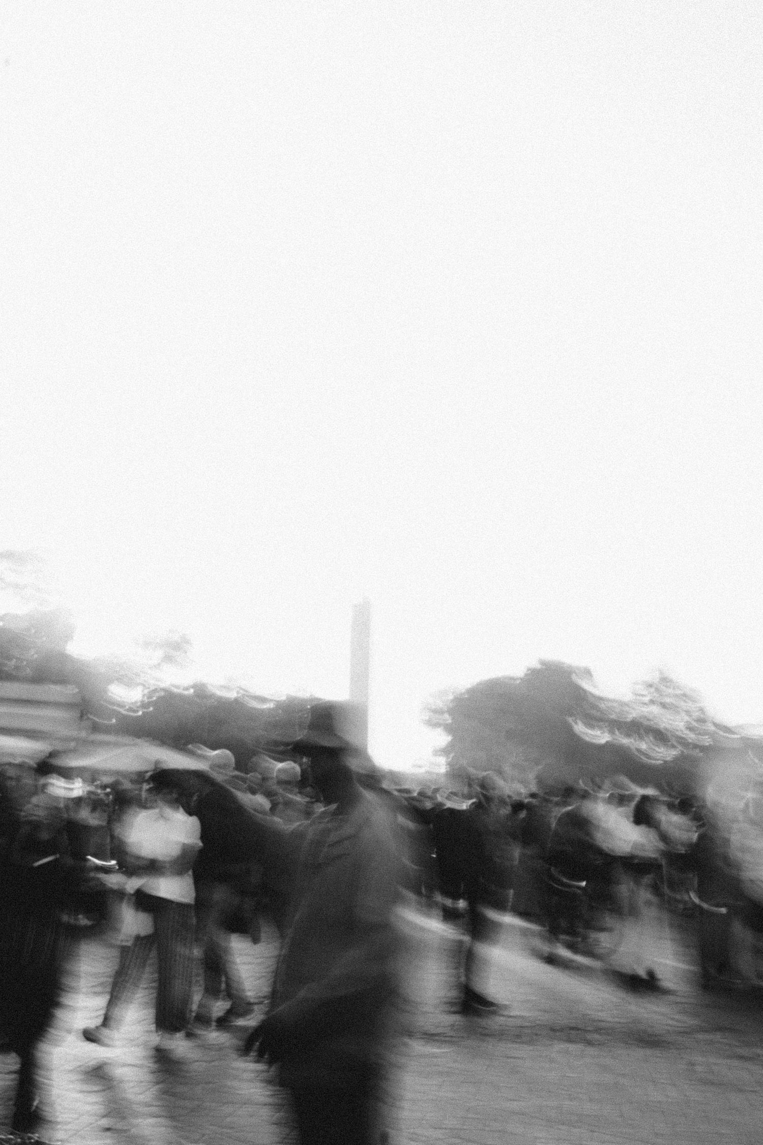 Blurred black and white motion photograph of people in a crowd.