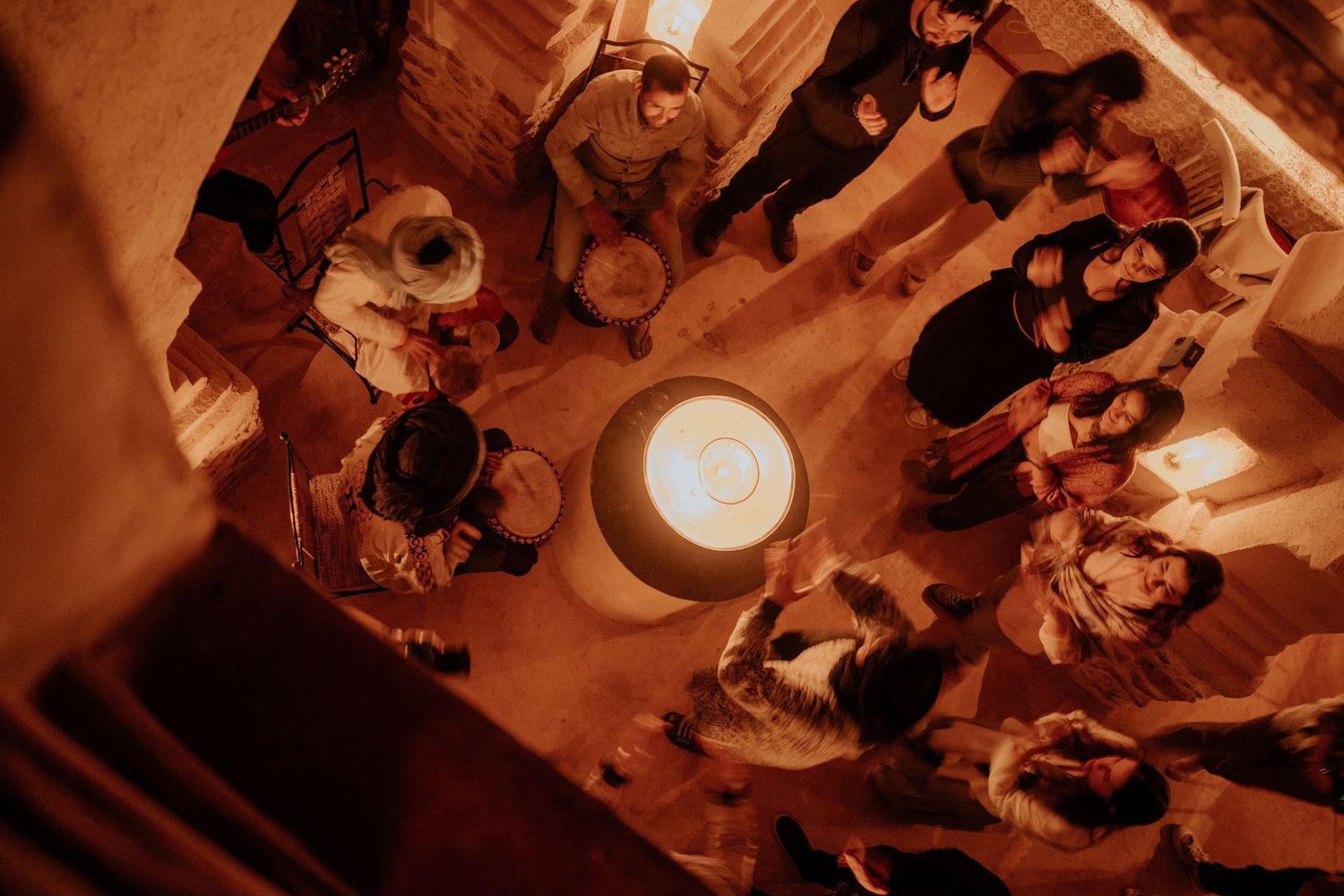 Overhead view of people gathered around glowing light in traditional Moroccan setting.