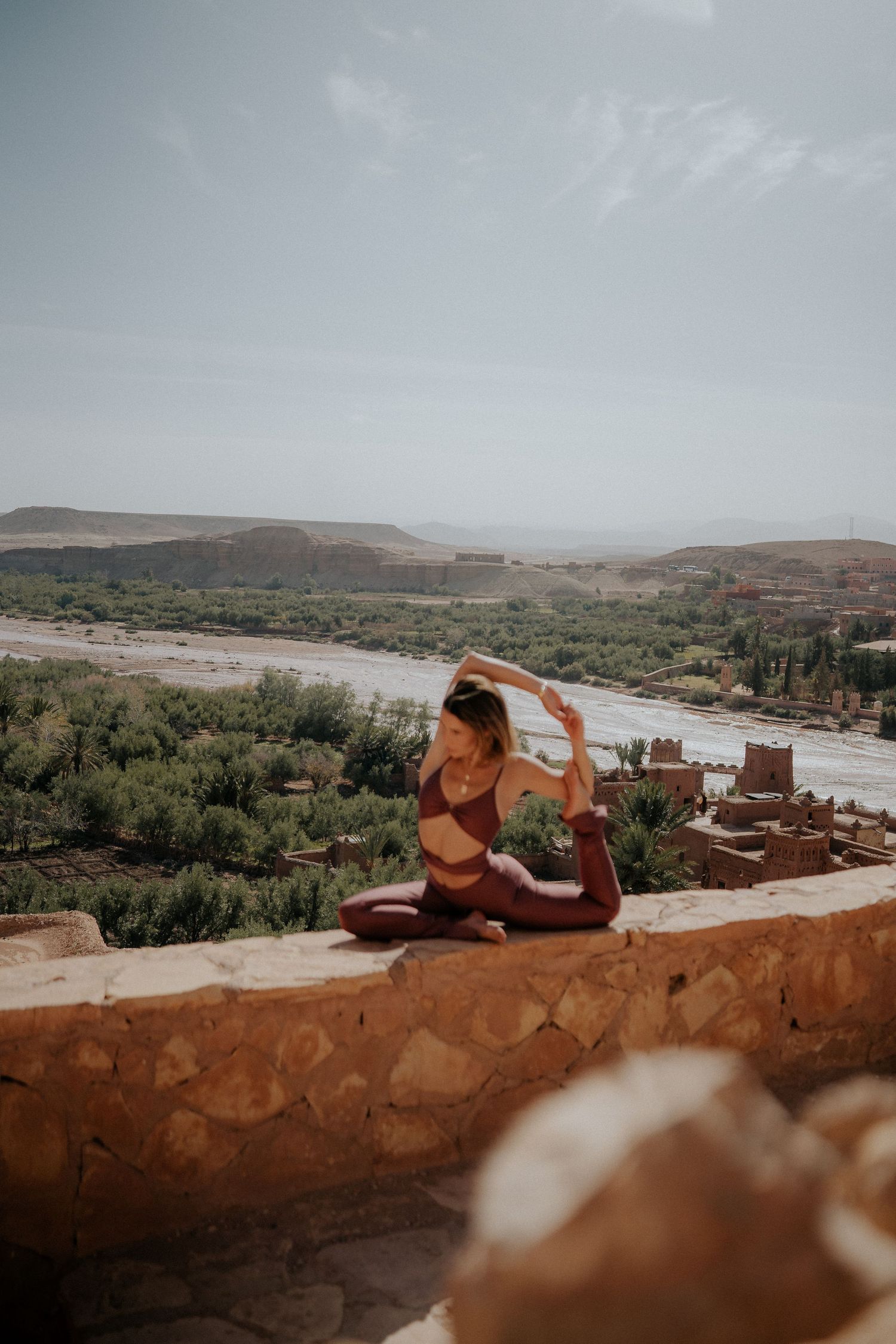 Scenic overlook of Moroccan river valley with ancient clay buildings and desert landscape.