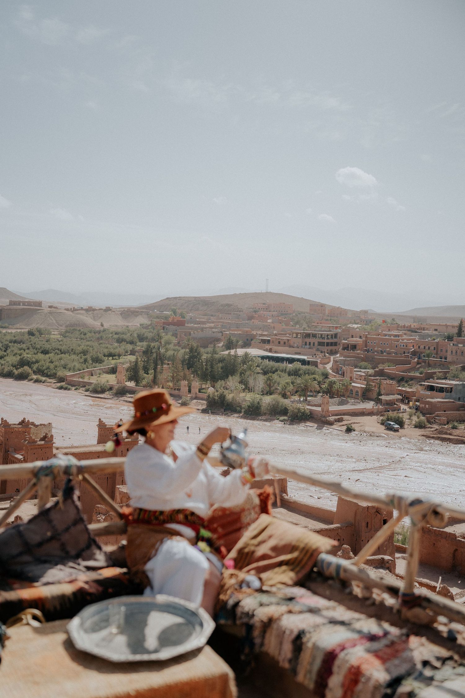 Scenic rooftop dining setup overlooking Moroccan desert valley and historic buildings.