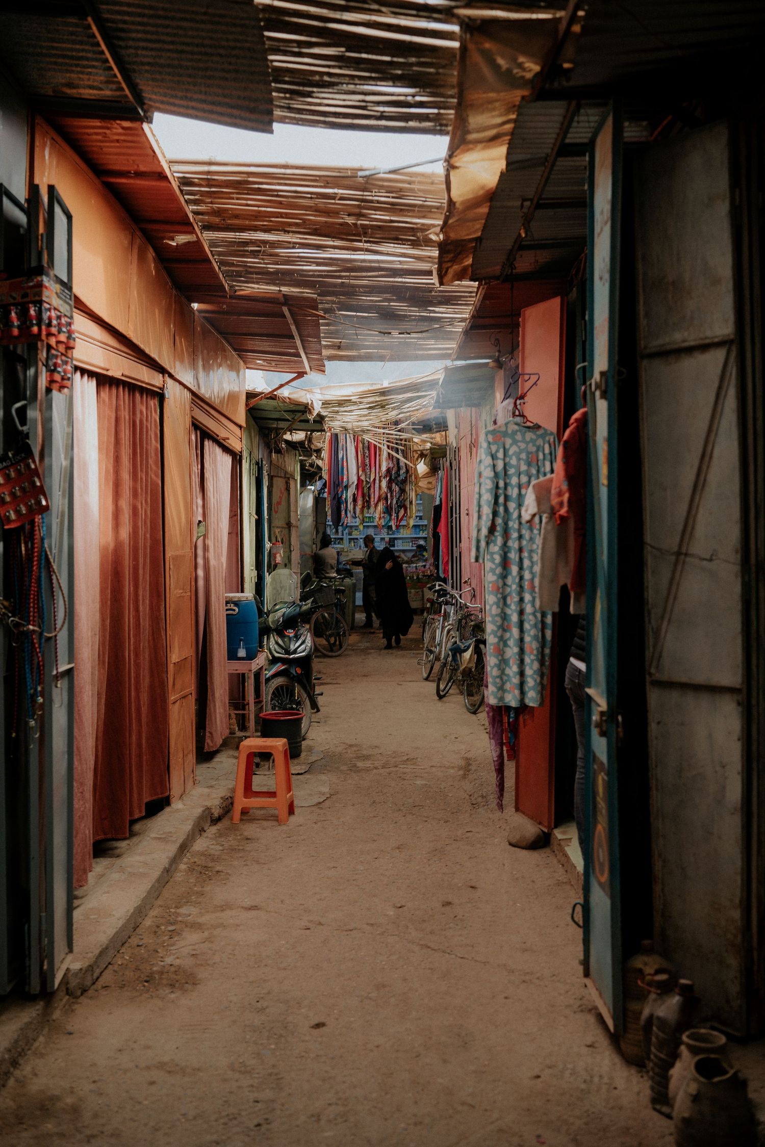 A long dimly lit corridor with fabric stalls and shops on both sides.