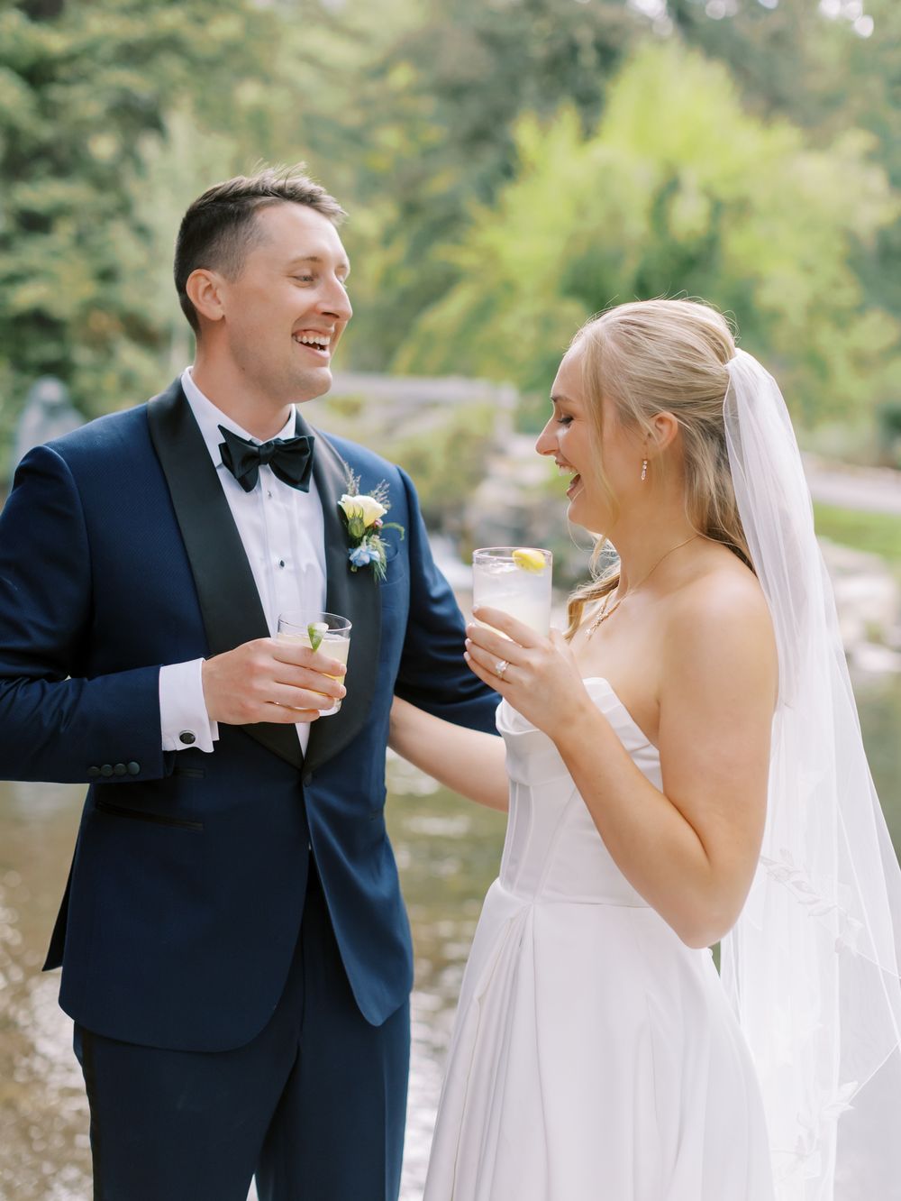 Happy couple sharing a candid moment and laughing together during an outdoor wedding ceremony.