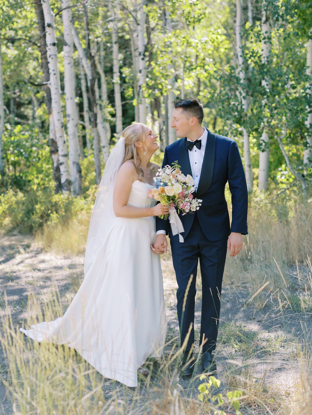 Newlyweds share intimate moments among white birch trees during their forest wedding photoshoot.