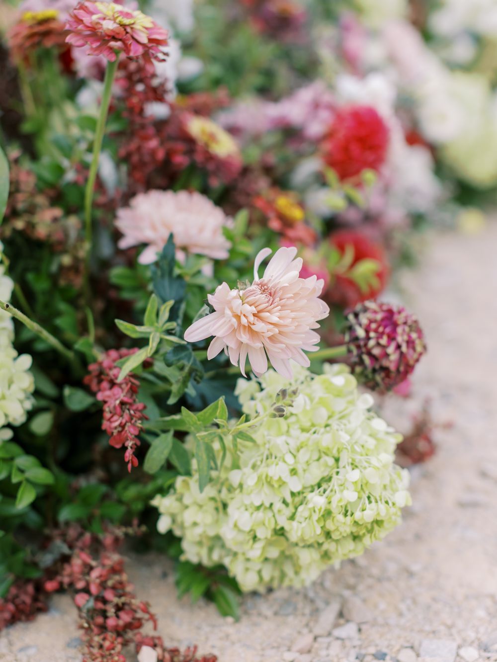 Delicate pink and white floral arrangements with dahlias and hydrangeas displayed against a textured surface.