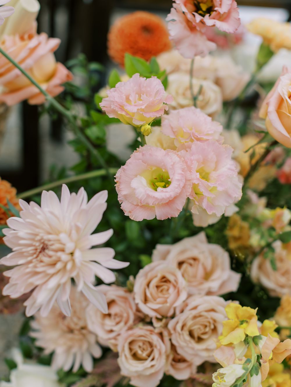 Delicate peachy-pink dahlias and roses create a soft, romantic wedding centerpiece.