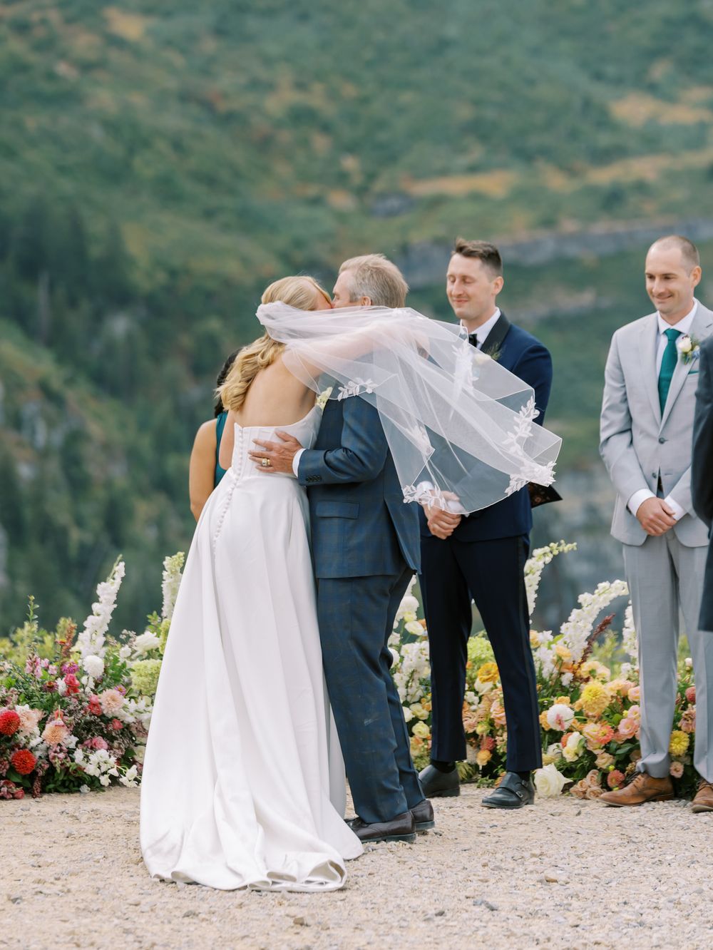 Emotional wedding ceremony moment on a scenic mountain overlook decorated with colorful flowers.