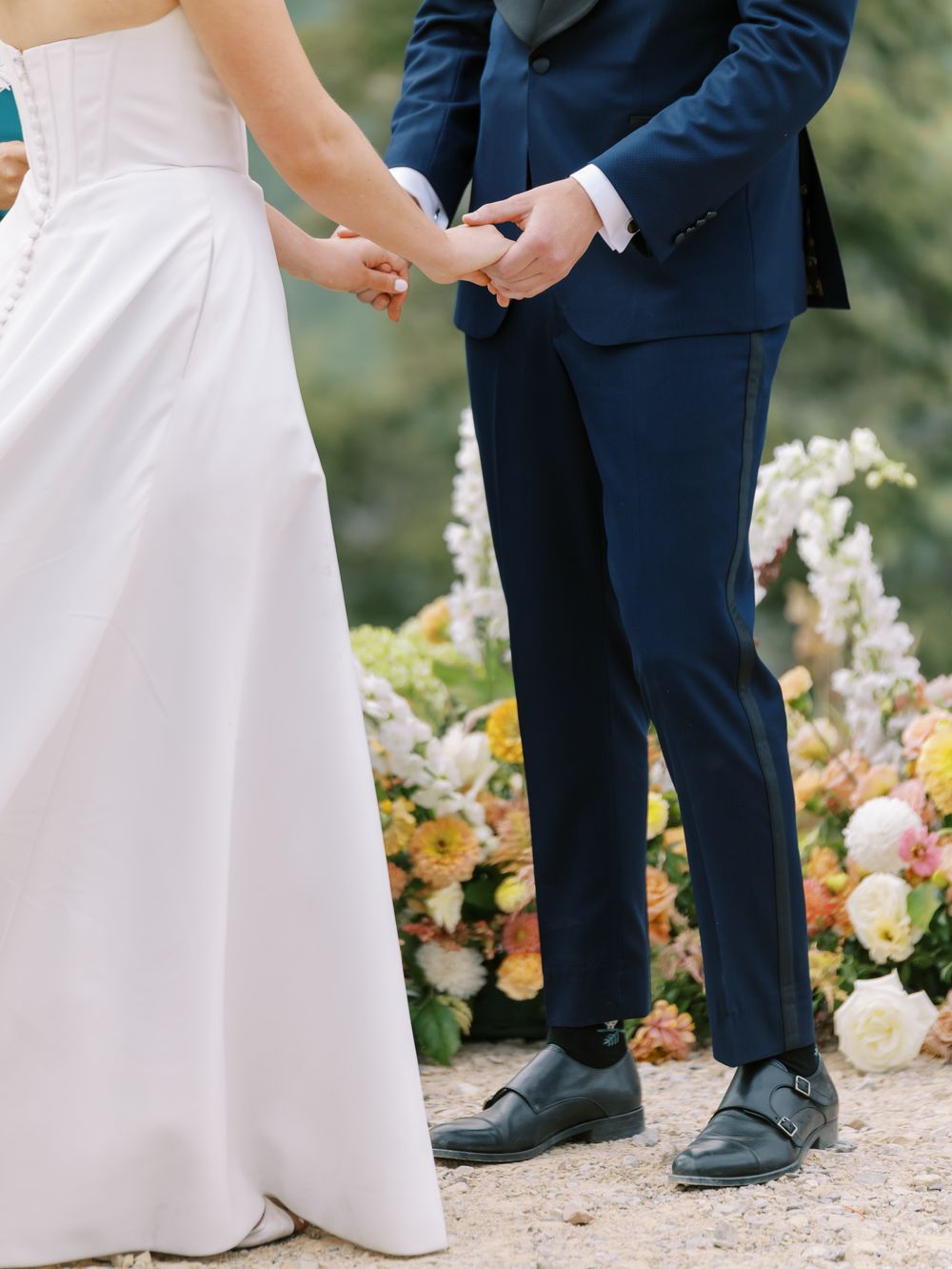 Close-up detail shot of wedding attire and floral arrangements during an outdoor ceremony.