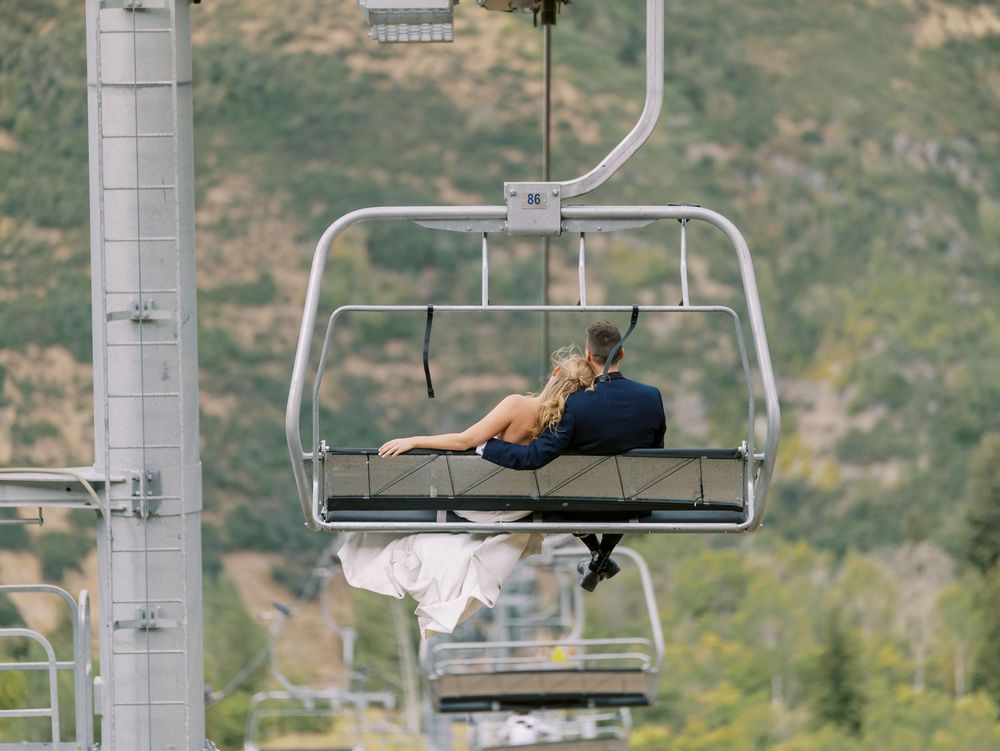 Ski lift chairs ascending a green mountainside during summer at a mountain resort.