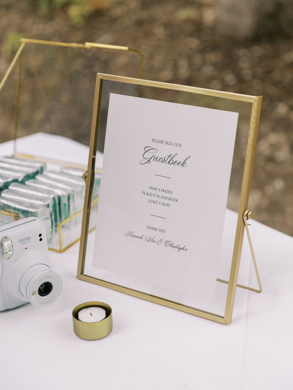 Elegant gold framed signs and table decor alongside white candles for a minimalist wedding reception setup.