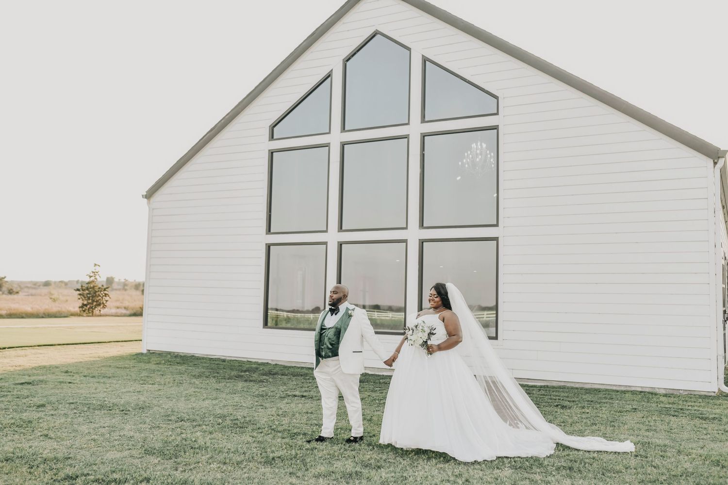 a bride and groom pose in front of the chapel at the gardenia wedding venue