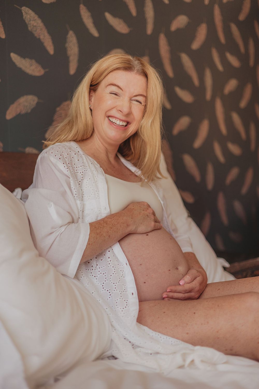 Intimate maternity moments captured on soft white bedding.