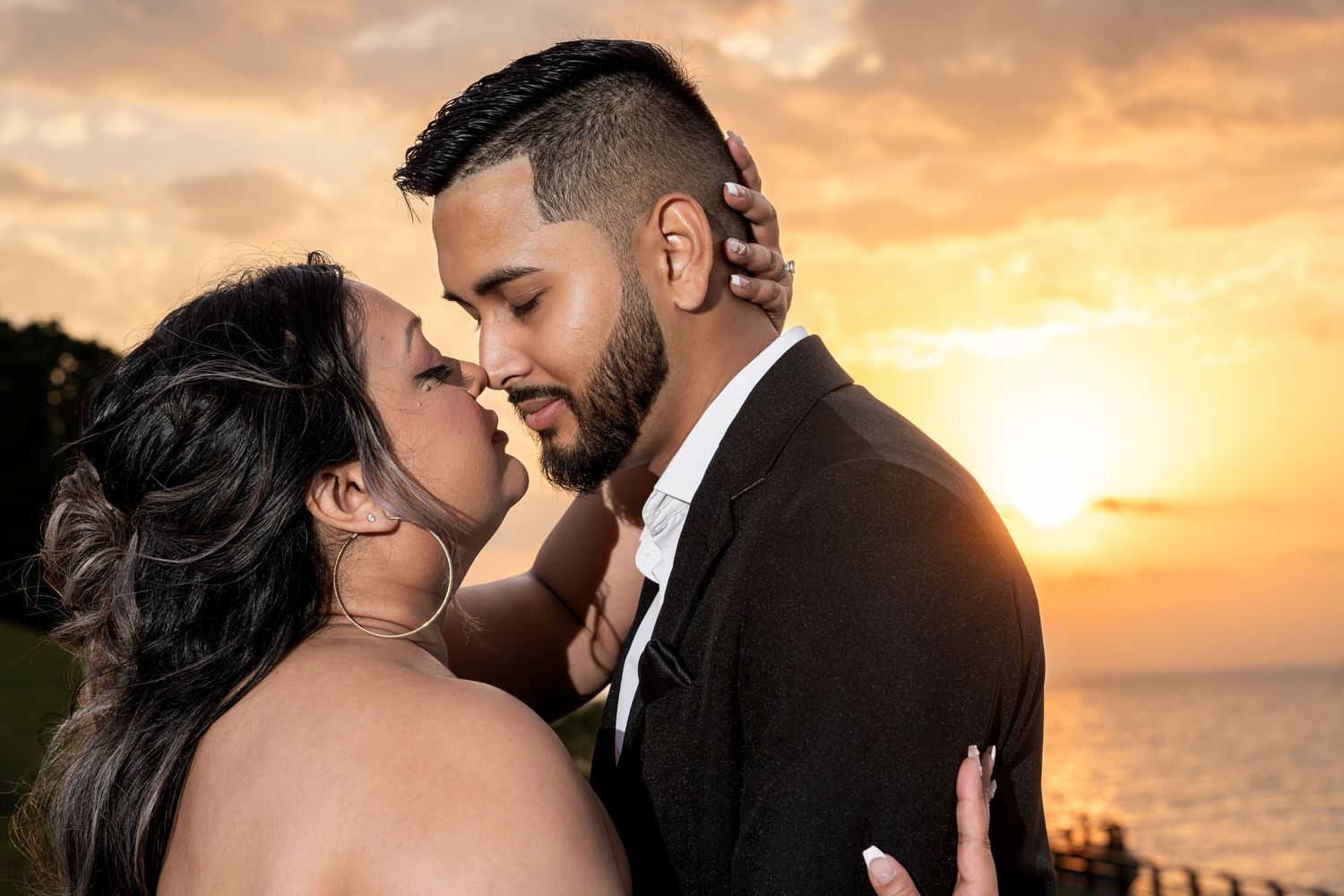 A romantic sunset silhouette session showcasing tender moments between a couple on a beach.