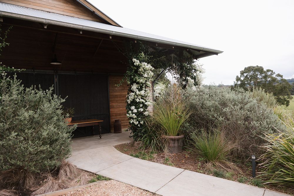 A modern wooden house exterior with multiple sliding glass doors and landscaped garden features.