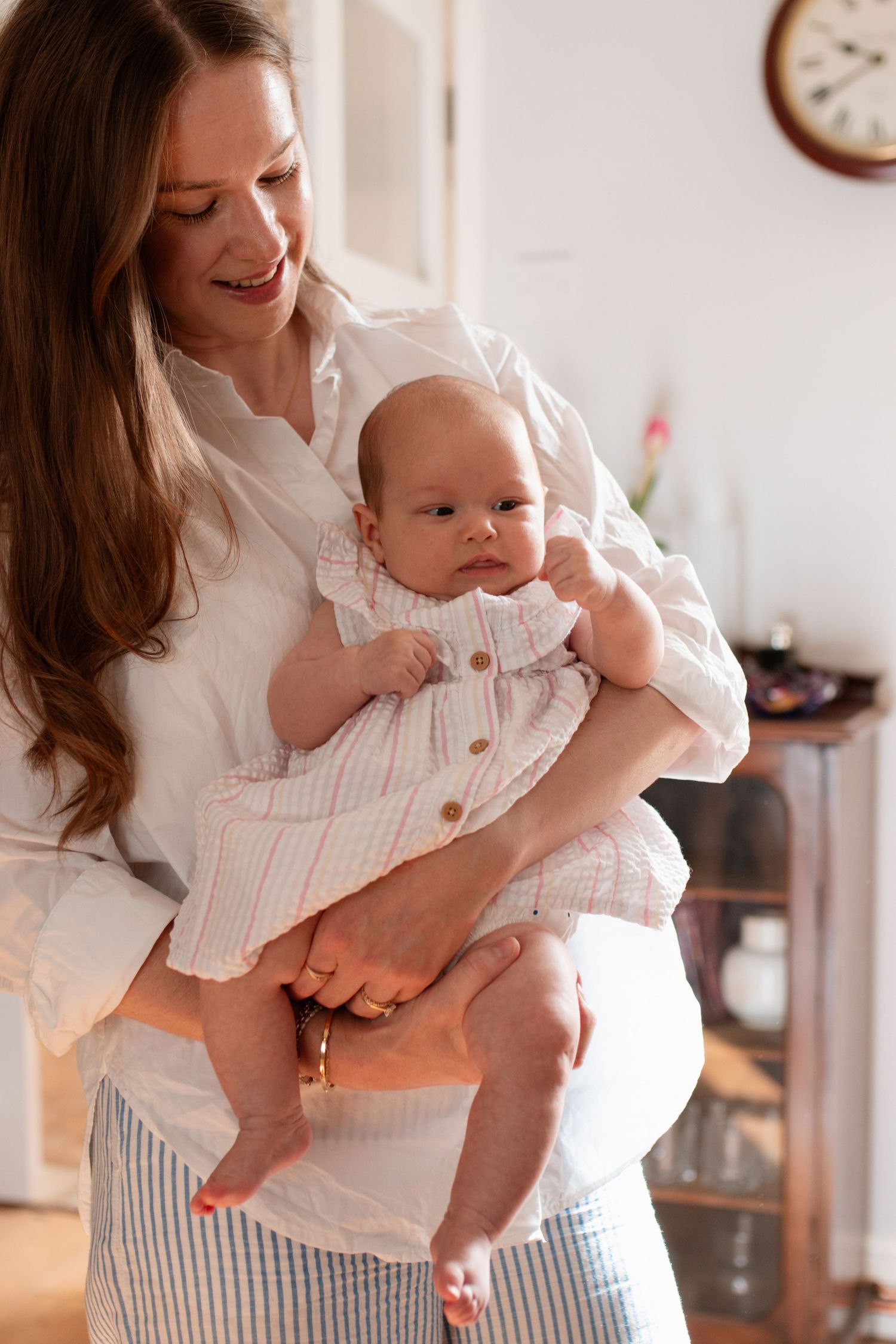 Parent playing with baby wearing matching white outfits in bright indoor setting.