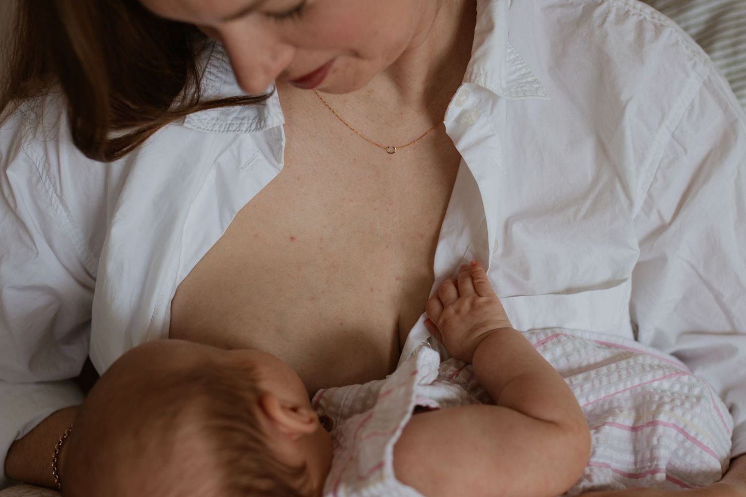 Tender moment between parent and baby in white clothing.