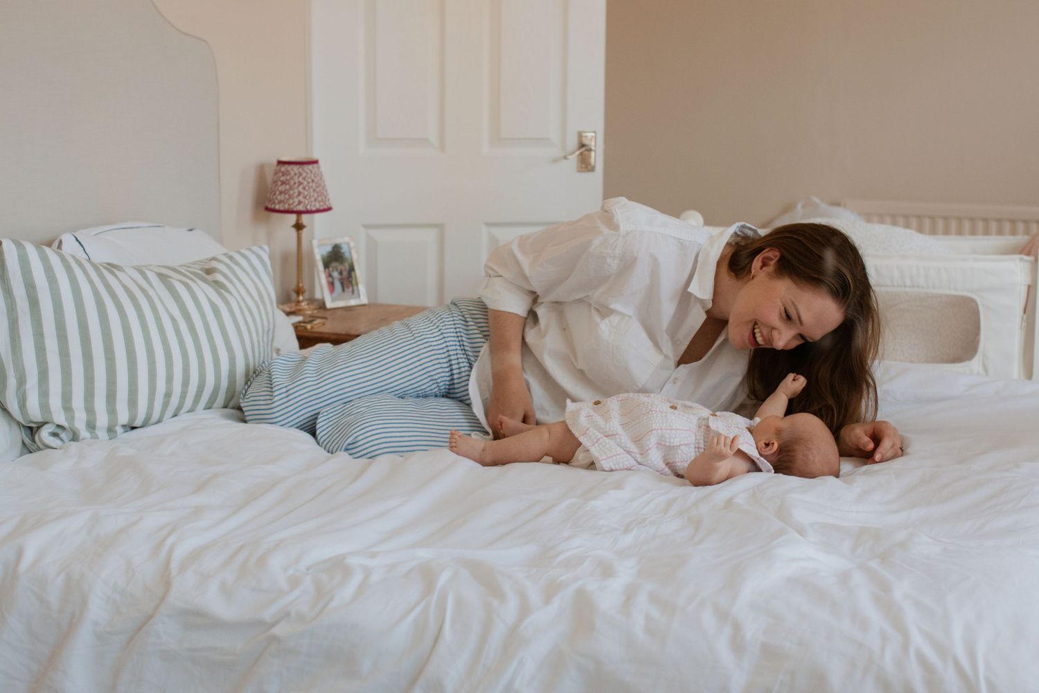 Peaceful moments captured of parent and baby resting on bed in natural light.