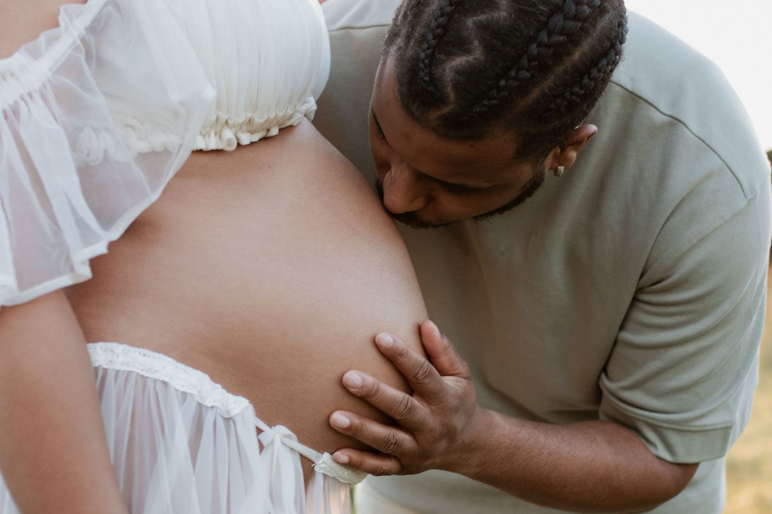 Tender moment during outdoor maternity photoshoot in natural lighting.