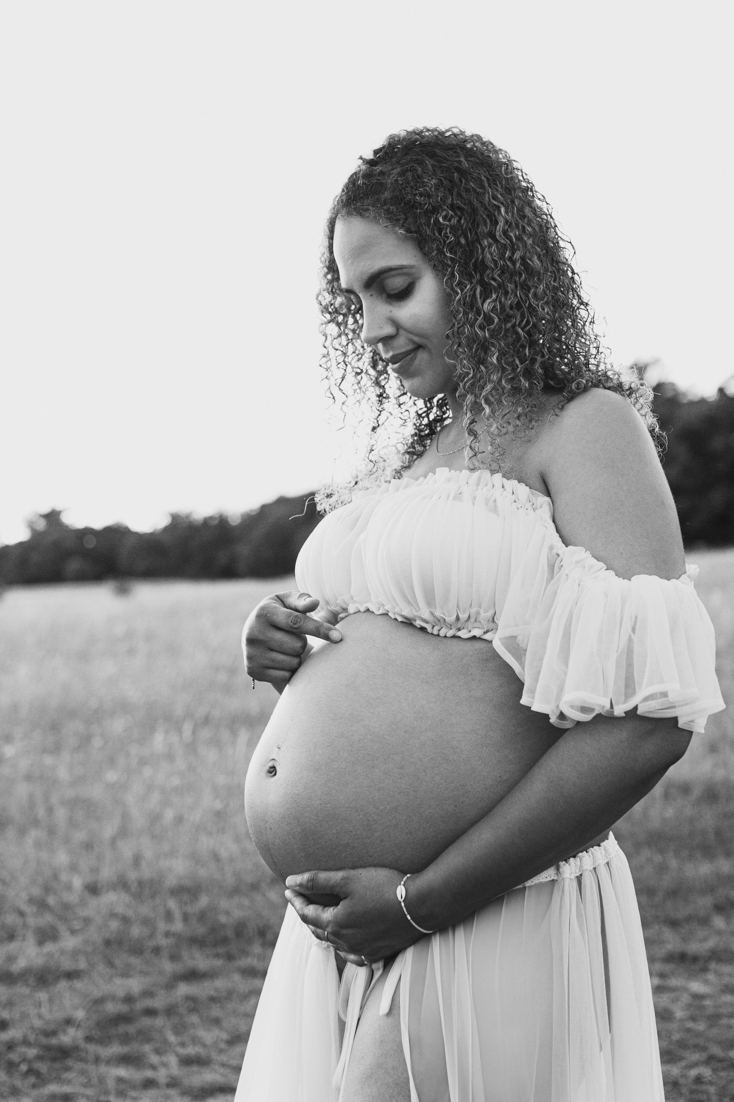 Black and white portrait of expectant mother in white off-shoulder dress.