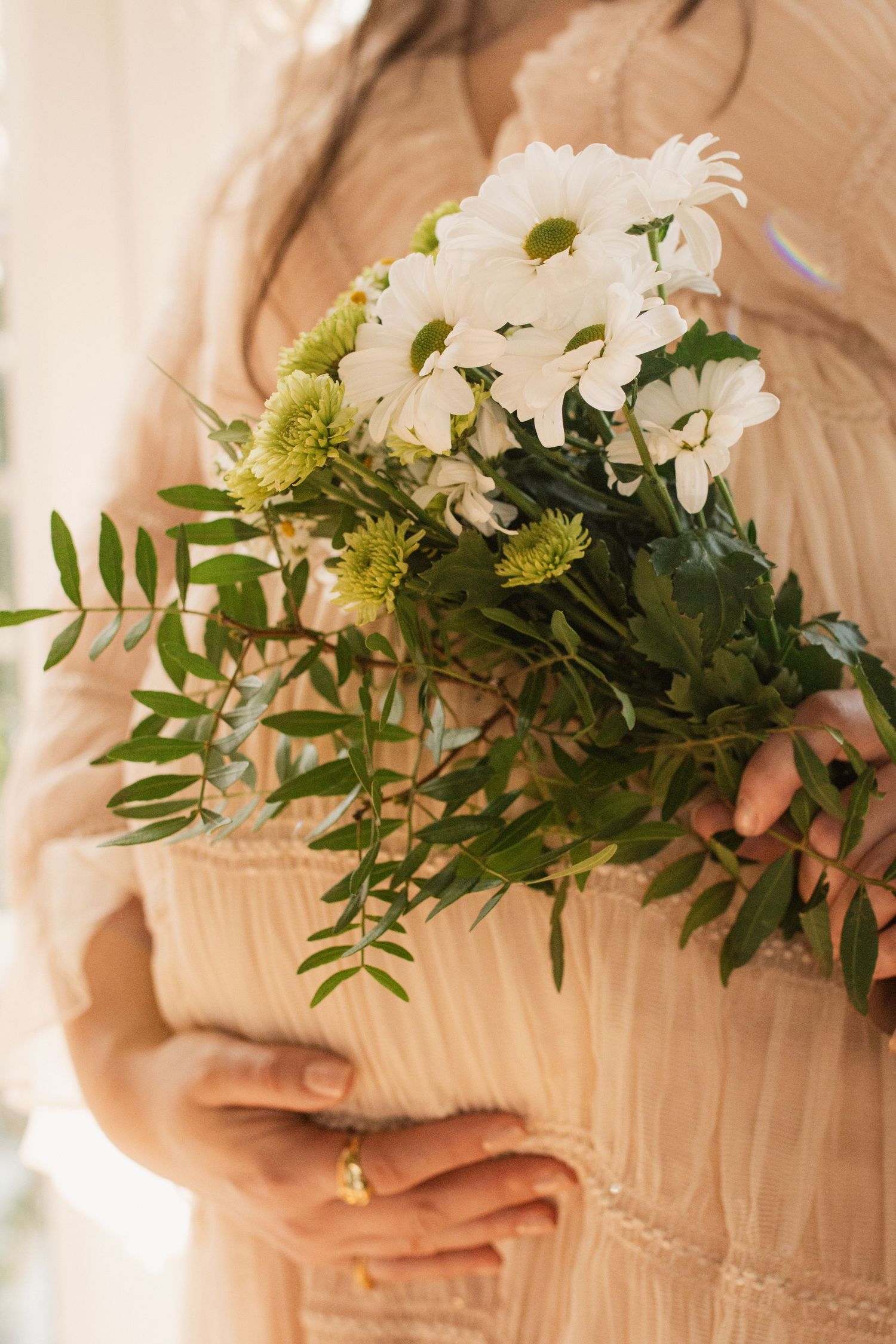 Close-up of white and green floral bouquet held against textured dress.