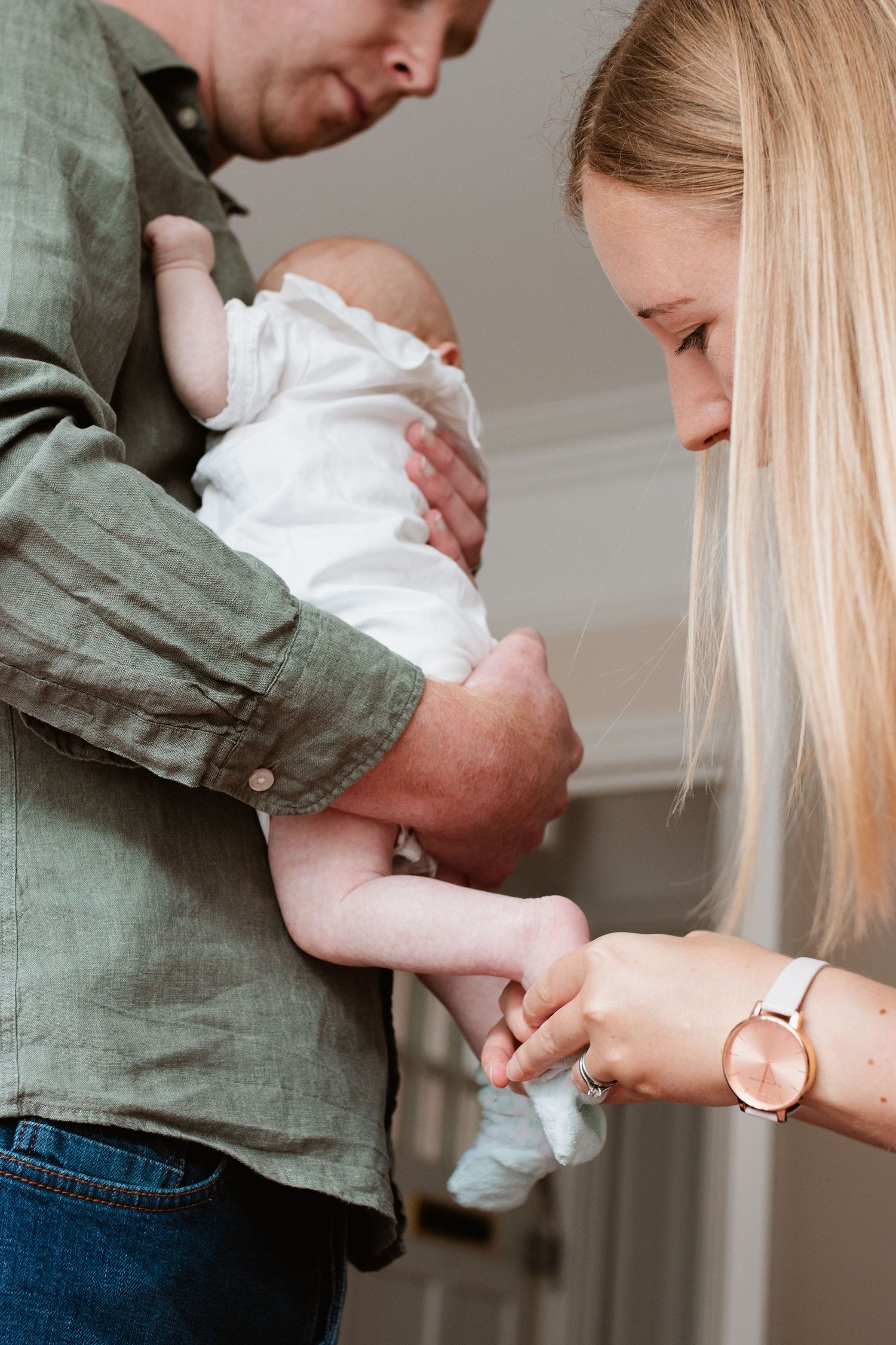 Tender moments captured between parent and newborn baby in white clothing against soft lighting.