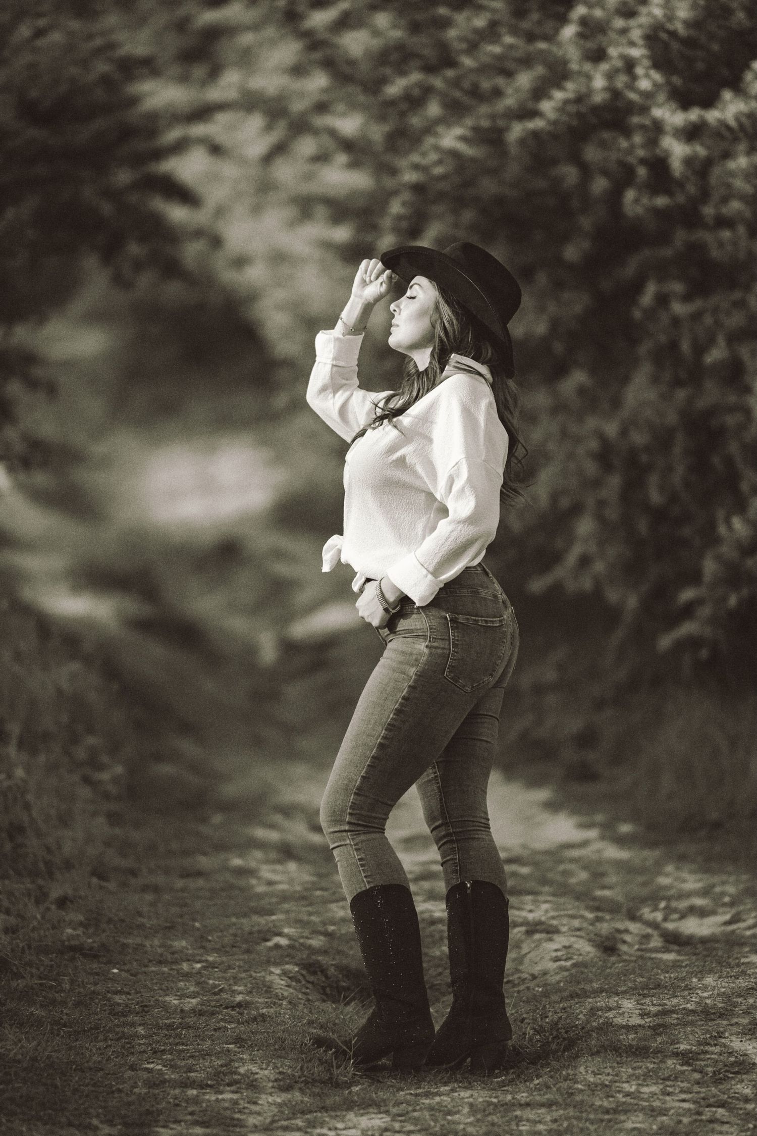 Svartvitt porträtt – kvinna i jeans och cowboyhatt i konstnärlig pose | Kreativ porträttfotograf Skåne