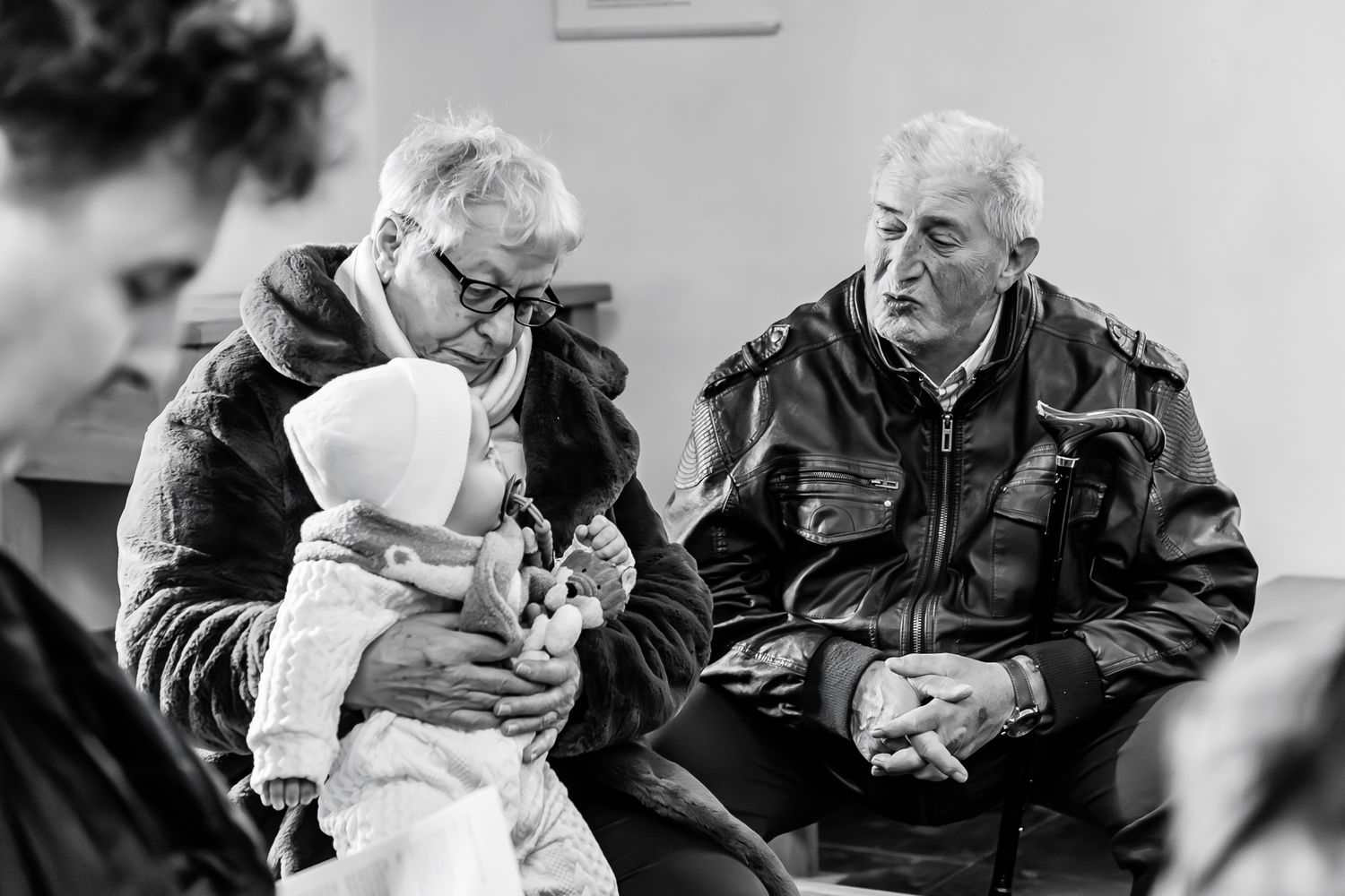 A heartwarming black and white photo showing three generations conversing together on a bench.