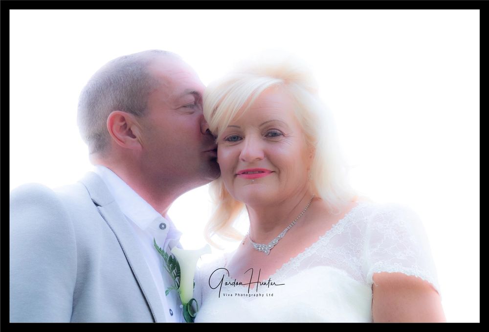 Romantic bride and groom sharing intimate moments in soft-focus wedding photography.