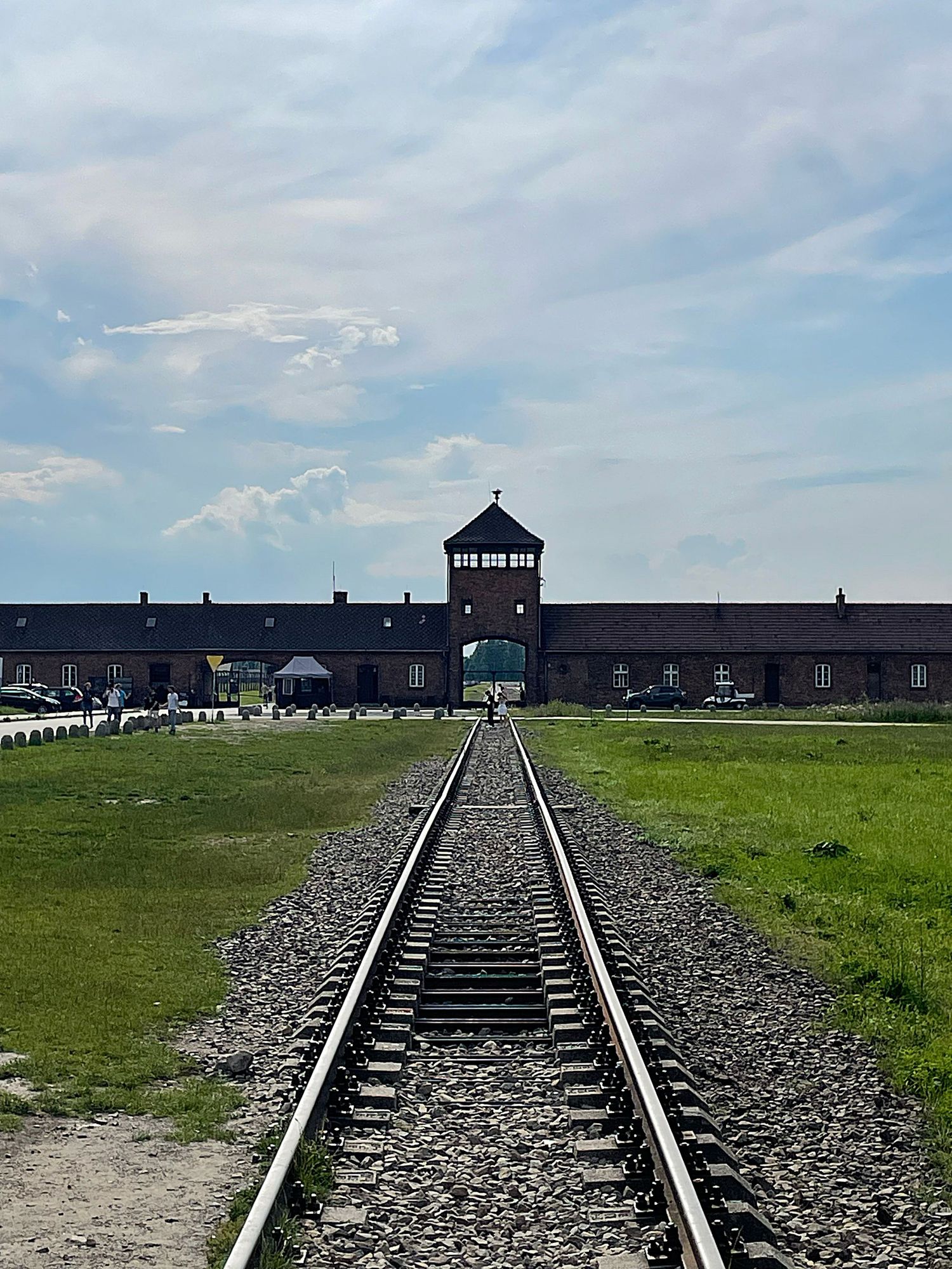 Train tracks leading to entrance gate buildings at Auschwitz-Birkenau concentration camp memorial site in Poland.
