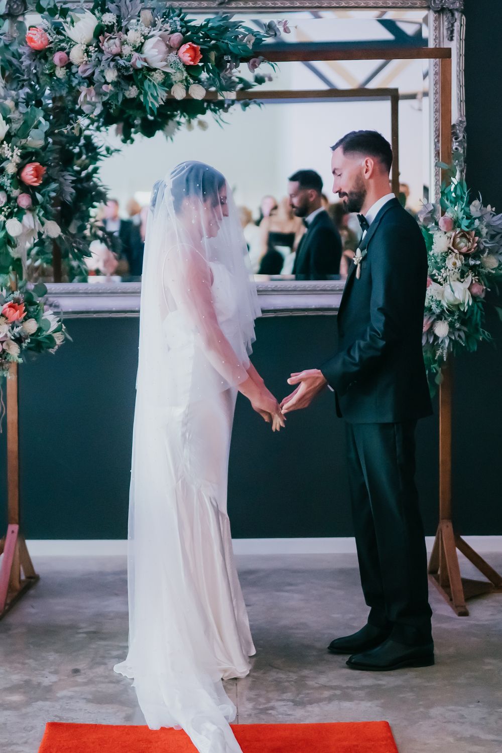 A bride and groom share a special moment under a floral arch during their wedding ceremony.