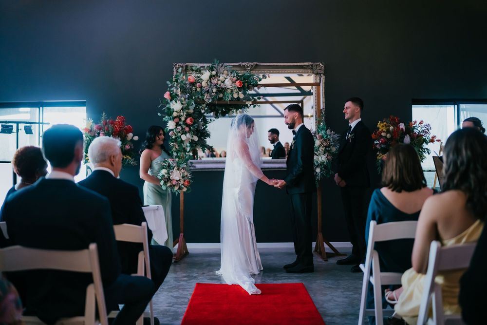 Couple shares a tender first dance in an intimate wedding reception venue with guests watching from the sides.
