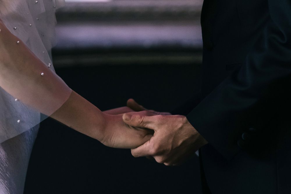 Two people shake hands in a dimly lit room with focused lighting from above.