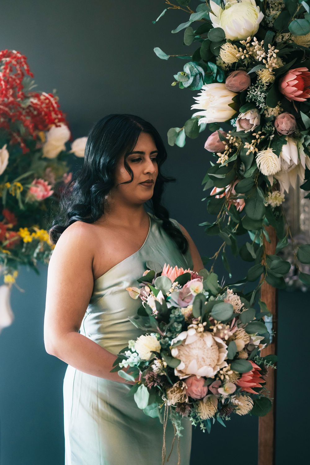 Elegant bridal portraits with lush floral arrangements featuring white roses and greenery against a dark backdrop.