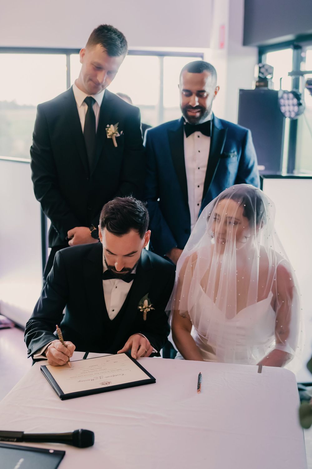 A series of wedding ceremony photos showing the signing of marriage documents by the couple and witnesses.