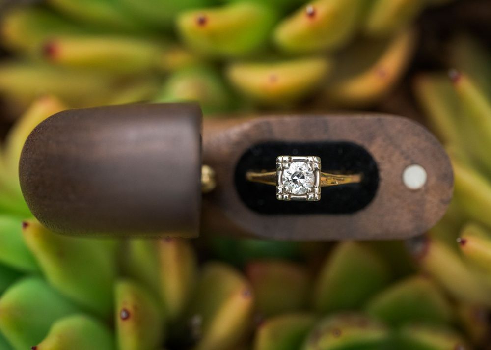Close-up view of a diamond engagement ring displayed on a rustic wooden surface.