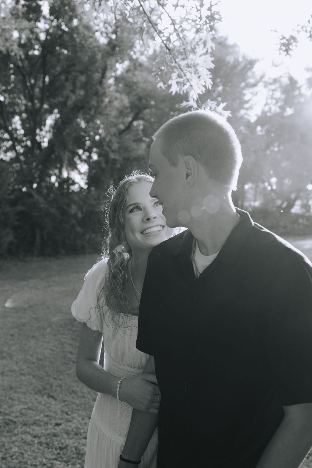 A romantic black and white photo sequence shows a couple embracing and laughing together outdoors in a natural setting.