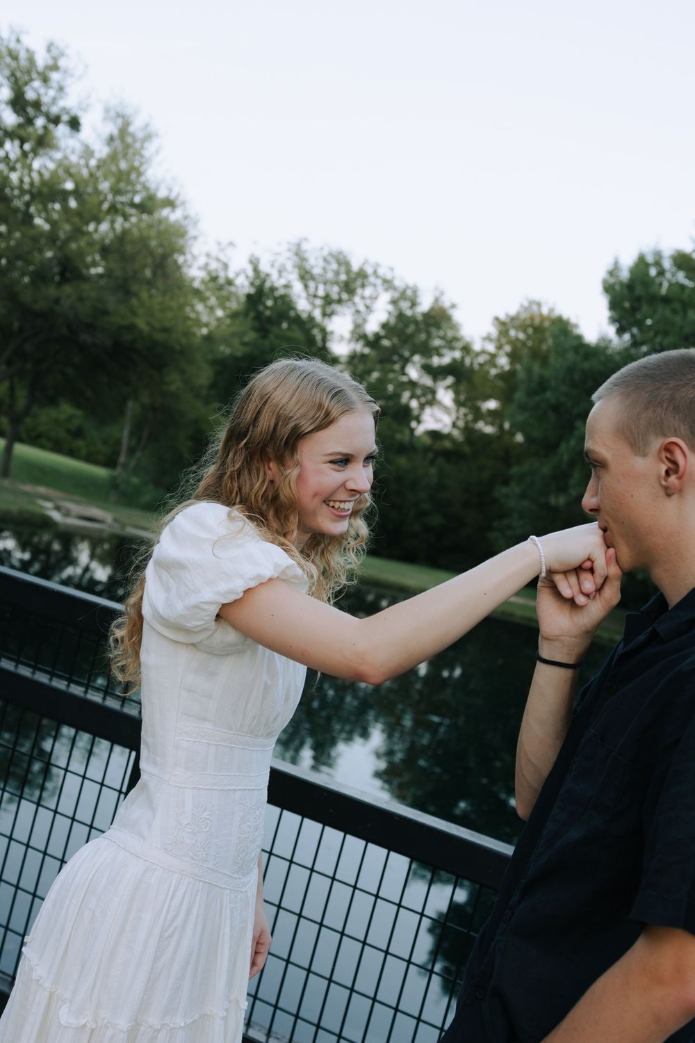 A couple shares a tender moment while sitting by a waterfront railing.