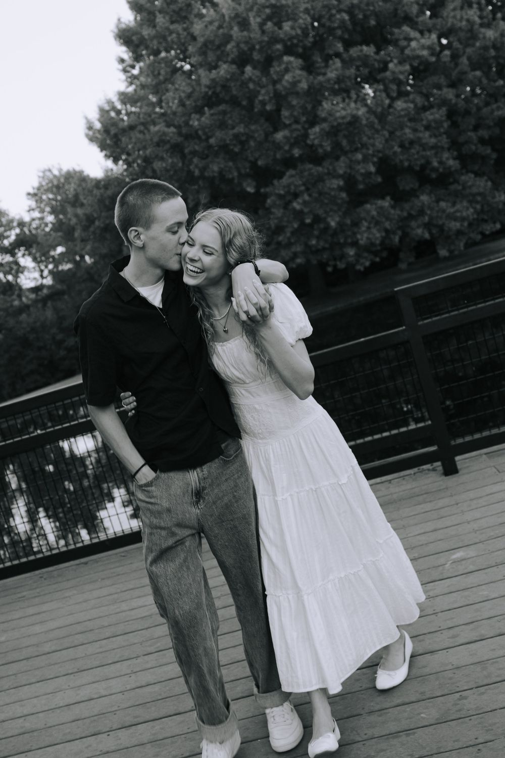 Black and white photo of a playful couple embracing on an outdoor deck.