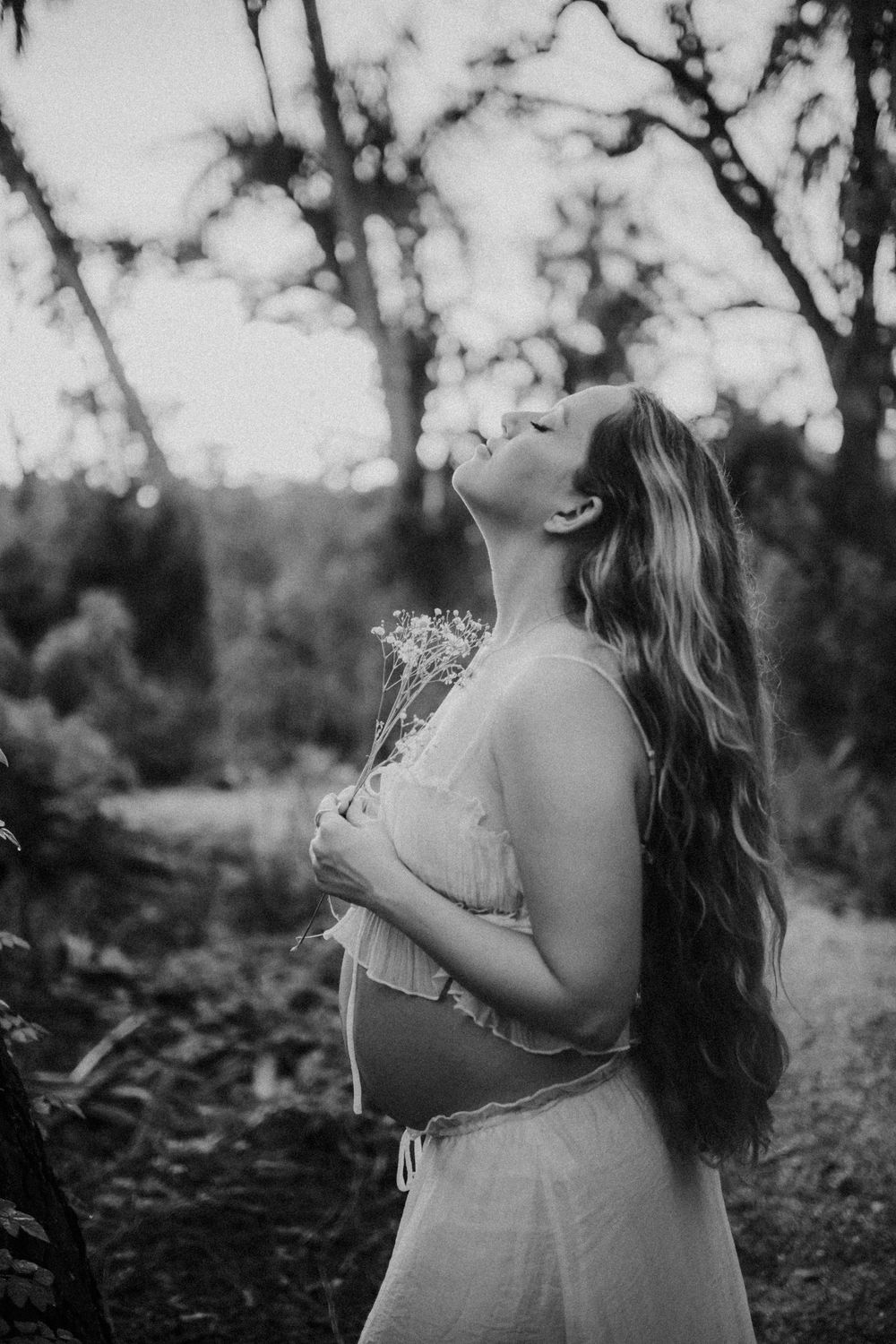 Black and white artistic photo series showing a woman in a dress standing outdoors among trees and foliage. sarasota family photographer