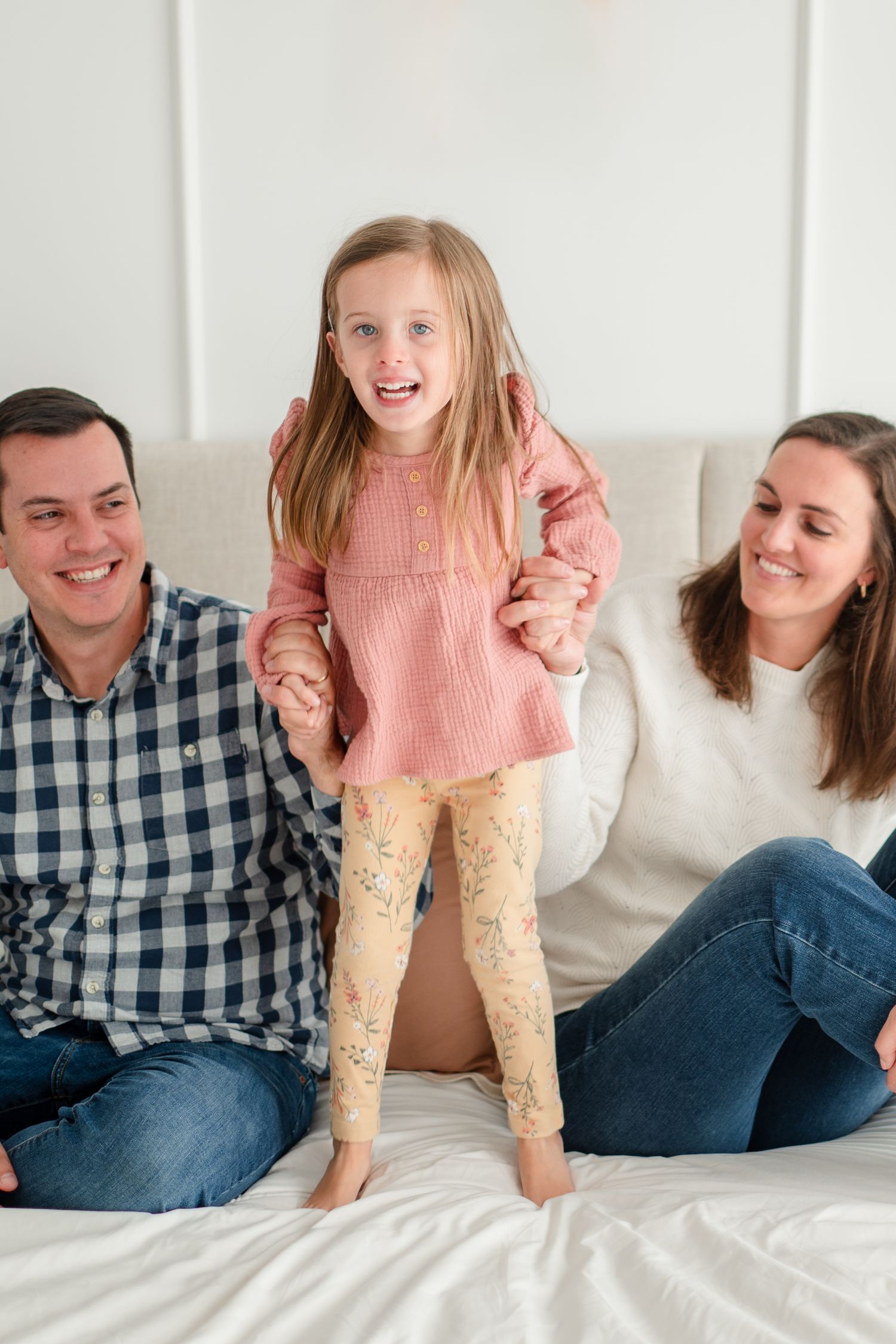 Family spending quality time together while sitting on a white couch, playful and happy moment.