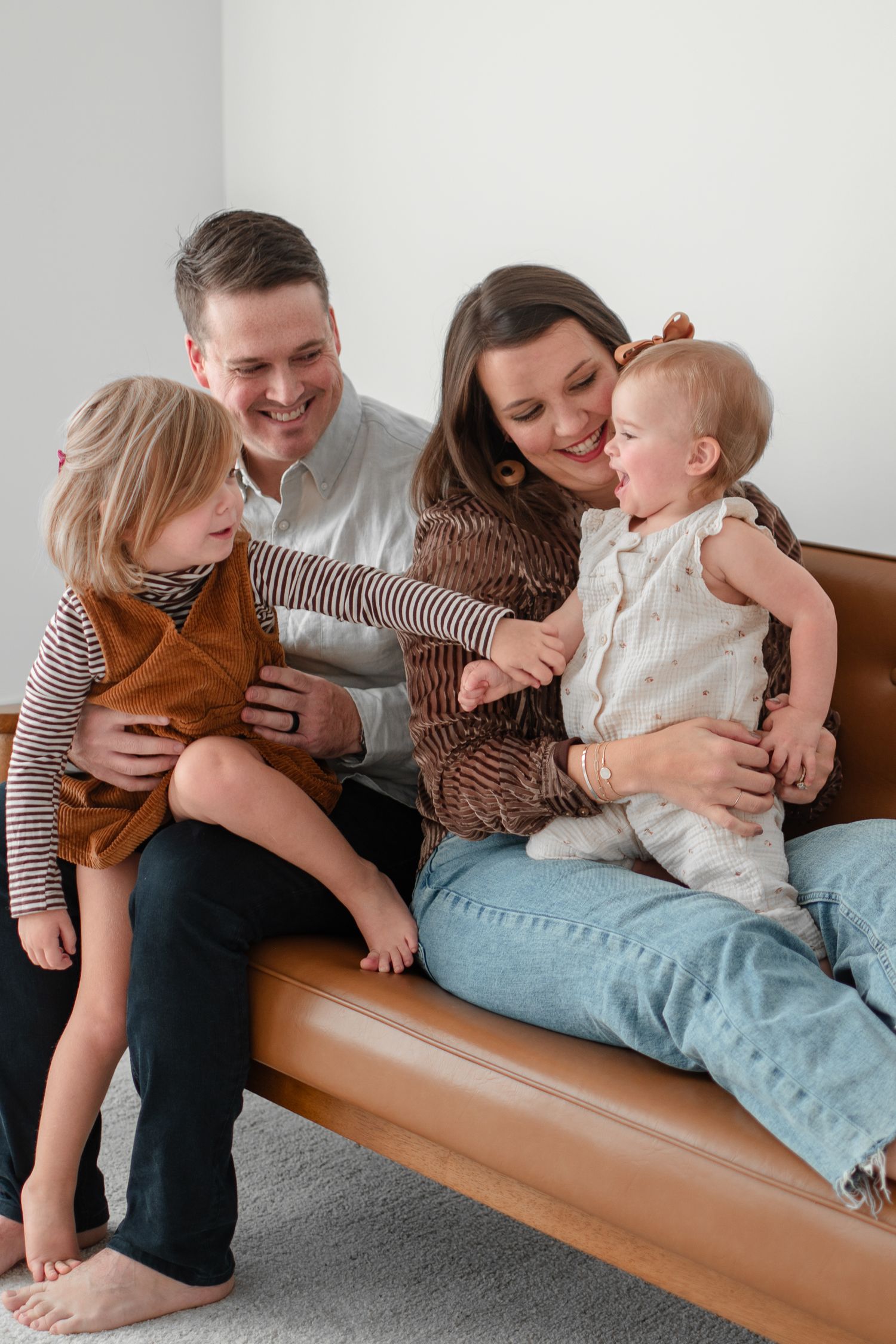 Family relaxes together on a modern wooden bench showing candid moments of affection and playfulness.