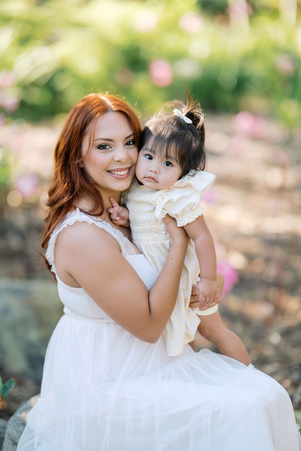 Sweet moments captured between parent and child wearing matching white dresses in a garden setting.
